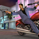 A man in a blue suit points a sub-machine gun at an off-screen target while riding a motorcycle.